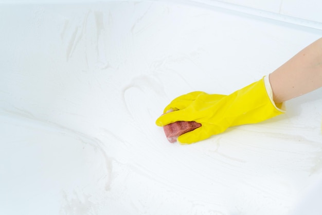 Eine Frau, die zu Hause ein Bad putzt Weibliche Waschbadewanne in Gelb