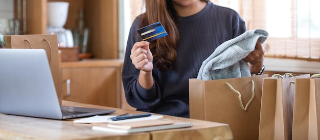 Eine Frau, die zu Hause einen Laptop und eine Kreditkarte für den Online-Einkauf verwendet