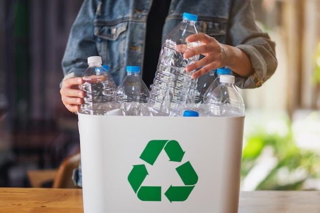 Eine Frau, die zu Hause recycelbare Plastikflaschen sammelt und in einen Mülleimer trennt