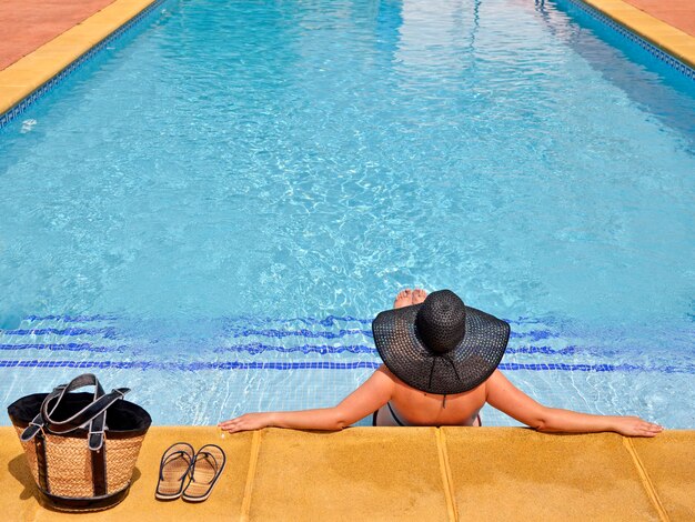 Foto eine frau entspannt sich am rand eines schwimmbades