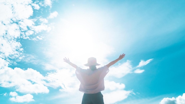 Eine Frau erhebt die Hand zum erstaunlich blauen Himmel und hat das Gefühl, nie aufzugeben und Freiheit zu haben