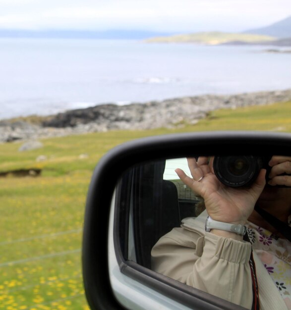 Foto eine frau fotografiert, wie sie sich im seitenspiegel spiegelt