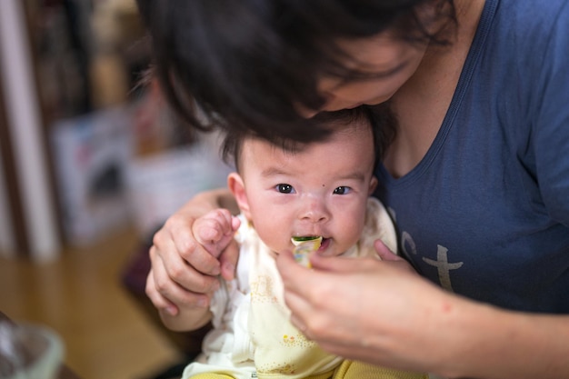 Eine Frau füttert ein Baby mit einem blauen T-Shirt mit der Aufschrift „Liebe liegt in der Luft“