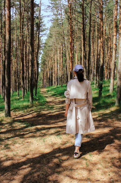 Eine Frau geht die Straße entlang durch einen jungen Kiefernwald