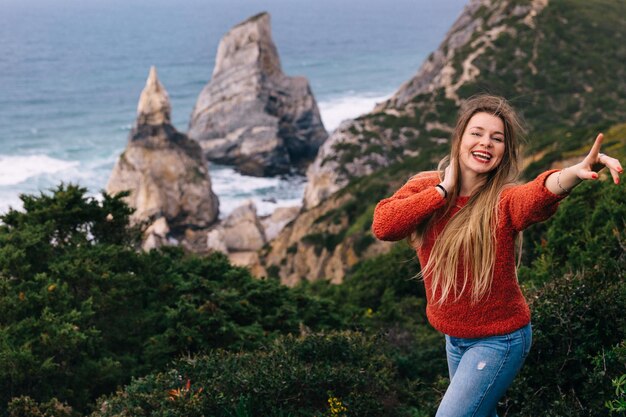 Eine Frau geht entlang eines felsigen Strandes am Ufer mit einem ruhigen Meer und einer grünen Natur im Hintergrund