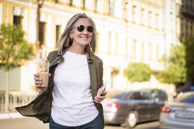 Foto eine frau geht mit einem getränk in der hand auf einer belebten straße spazieren