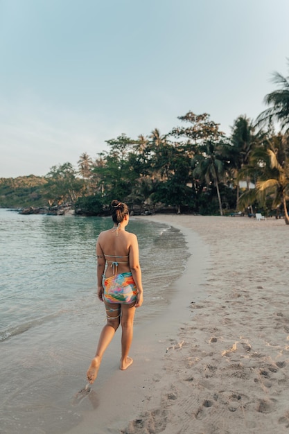 Eine Frau geht morgens am Strand spazieren