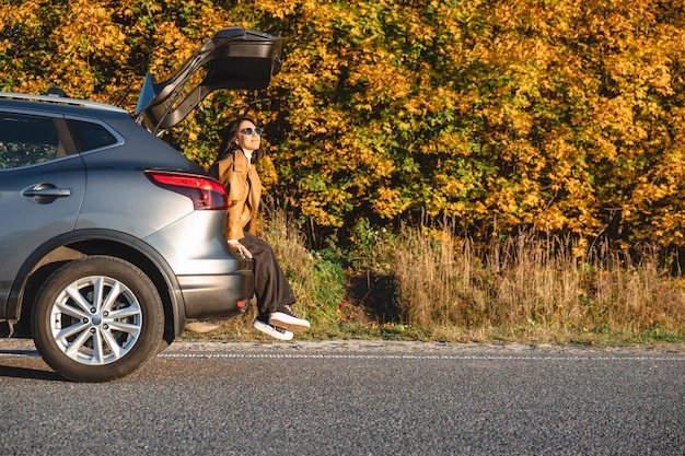 Eine Frau genießt die Sonne im Kofferraum eines Autos