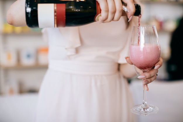 Eine Frau gießt rosa Champagner in ein Glas