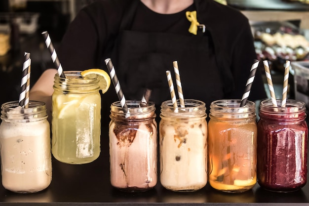 Eine Frau hält an einem heißen Sommertag ein erfrischendes Eisgetränk in den Händen Eisgetränke in Glasgefäßen mit recycelbaren Strohhalmen