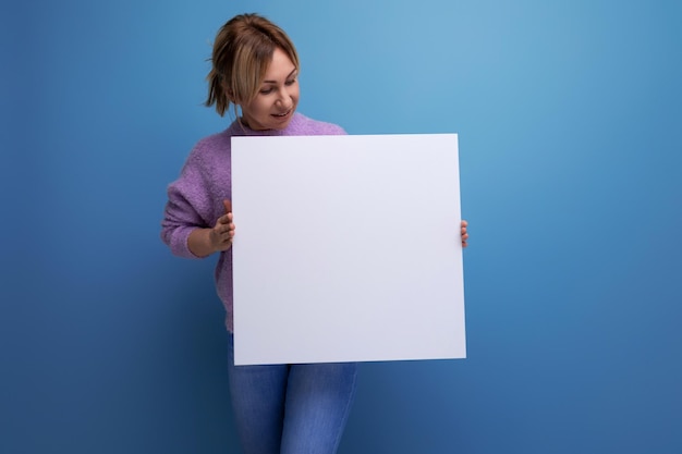 Eine Frau hält ein Blatt Zeichenpapier mit einem Modell für eine Werbebotschaft auf blauem Hintergrund