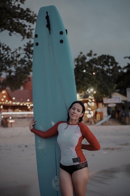 Foto eine frau hält ein surfbrett, während sie am strand steht