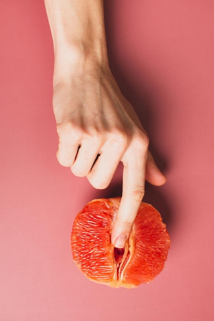 Eine Frau hält eine Grapefruit an ihrem Höschen Konzept-Masturbation