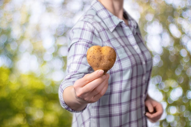 Foto eine frau hält eine herzförmige kartoffel in der hand.