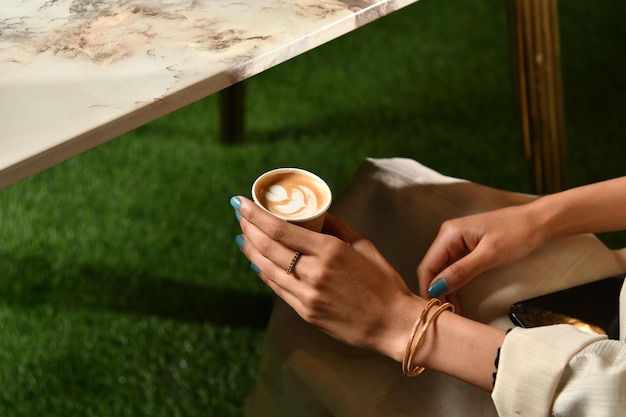 Eine Frau hält eine Tasse Kaffee mit Latte Art darauf.