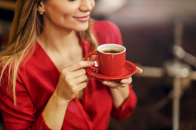 Eine Frau hält eine Tasse Kaffee neben einer Röstmaschine