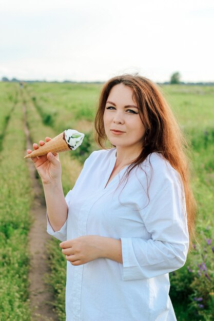 Eine Frau hält einen Kegel mit Eis am Stiel in ihren Händen. Cooles Dessert im Sommer.