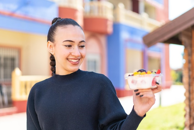 Eine Frau hält einen kleinen Obstbehälter und eine Obstkiste.