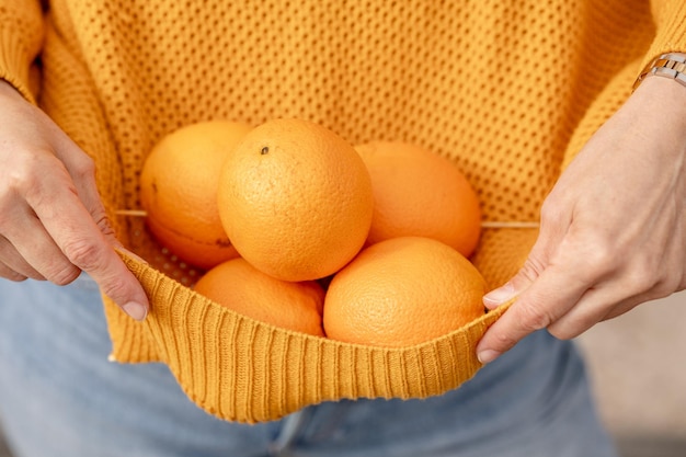 Eine Frau hält einen Korb mit Orangen.