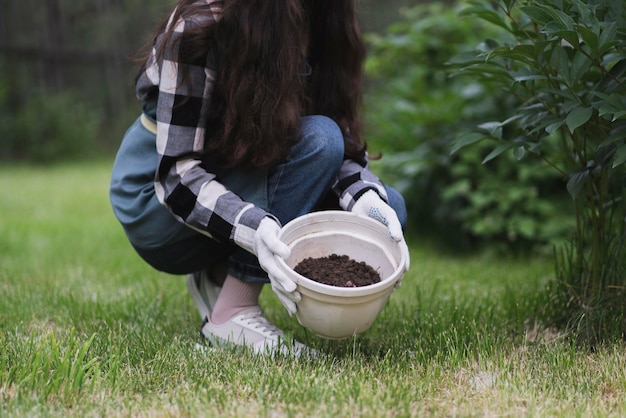 Eine Frau hält einen leeren weißen Topf in der Hand, um eine Blume hineinzupflanzen