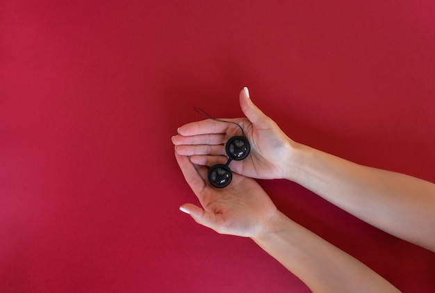 Eine Frau hält schwarze Vaginalkugeln für Muskelübungen bereit. Starke Vaginalmuskulatur