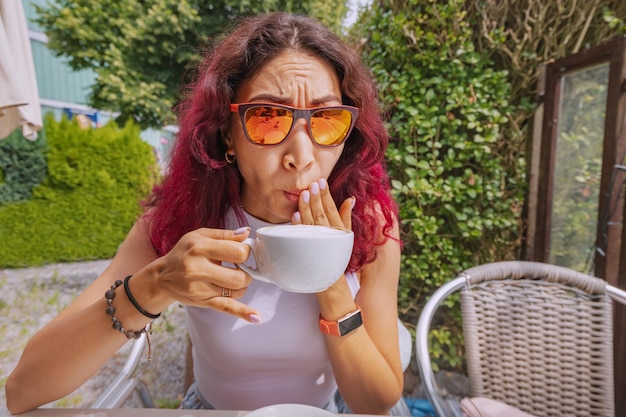 Eine Frau hat sich in einem Café mit sehr heißem Kaffee verbrannt und verspürt einen stechenden Schmerz im Mund