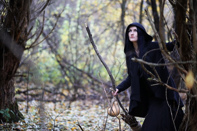 Eine Frau im Hexenanzug in einem dichten Wald bei einem Ritual