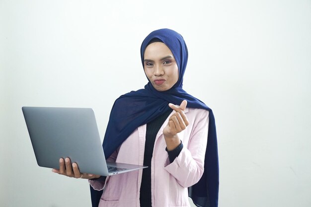 Eine Frau im Hijab hält einen Laptop und zeigt auf ihren Finger.