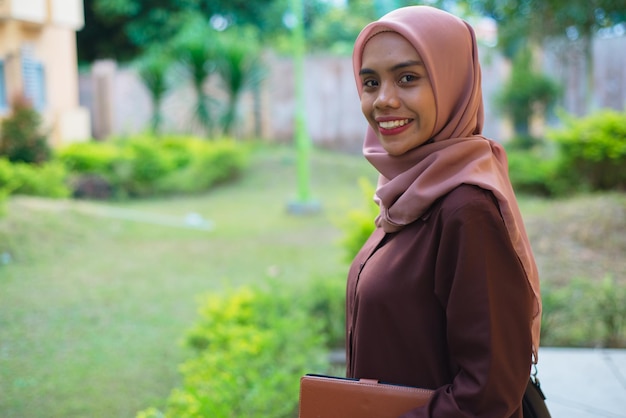 Foto eine frau im hijab mit einer mappe in der hand.