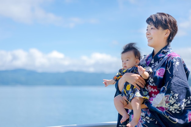 Eine Frau im Kimono hält ein Baby auf einem Boot im Wasser.