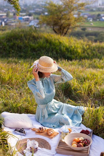 Eine Frau in blauem Kleid sitzt auf einem Picknick in einem Park mit Panoramablick