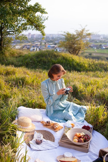 Eine Frau in blauem Kleid sitzt auf einem Picknick in einem Park mit Panoramablick