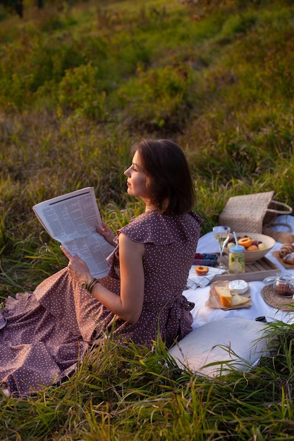 Eine Frau in braunem Kleid sitzt auf einem Picknick in einem Park mit Panoramablick