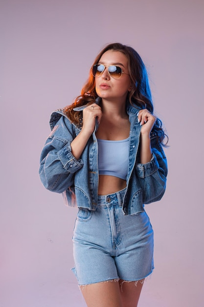 Eine Frau in Denim Shorts Sonnenbrille im Studio auf einem interessanten schönen Hintergrund