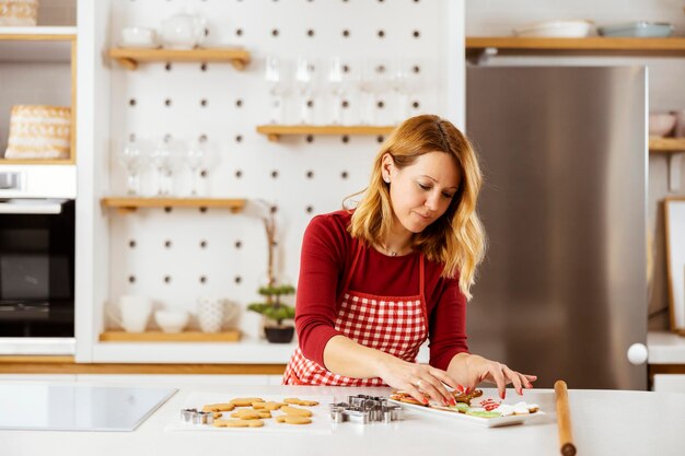 Eine Frau in der Küche arrangiert auf einem Teller Ingwer-Weihnachtskekse, die sie für Silvester gemacht hat
