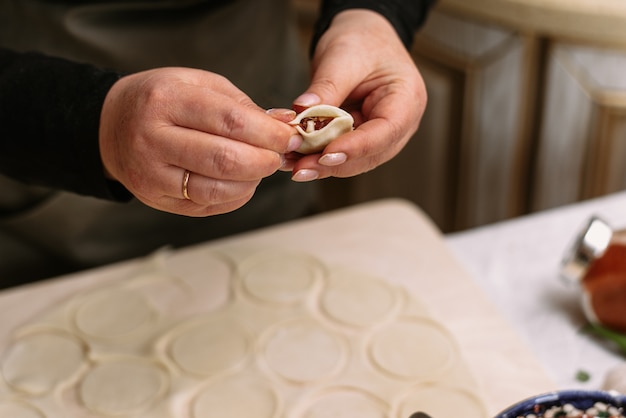 Eine Frau in der Küche formt hausgemachte Knödel oder Halbzeuge. Der Koch wickelt das Hackfleisch vom Rind in den Teig