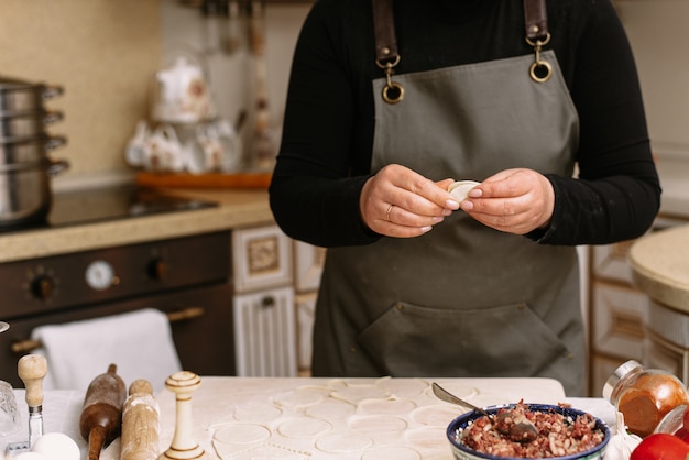 Eine Frau in der Küche formt hausgemachte Knödel oder Halbzeuge. Der Koch wickelt das Hackfleisch vom Rind in den Teig