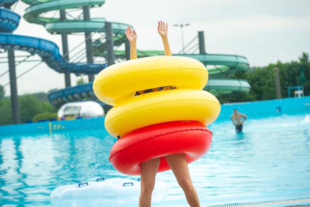 Eine Frau in einem Badeanzug mit aufblasbaren Gummikreisen spielt und hat eine gute Zeit in der Nähe des Pools des Sommerwasserparks.