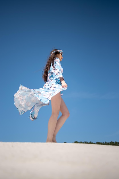 Eine Frau in einem blauen Kleid geht am Strand spazieren