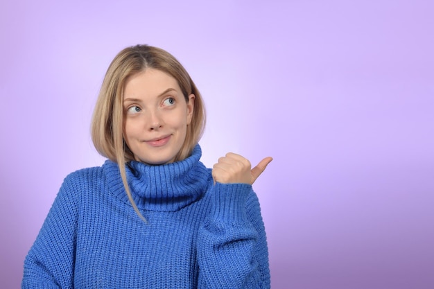 Eine Frau in einem blauen Pullover zeigt nach rechts.