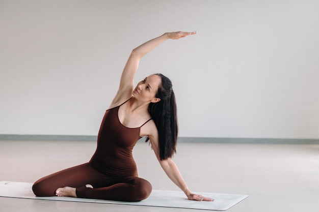 Eine Frau in einem braunen Anzug macht Yoga in einem Fitnessraum Gesunder Lebensstil Fitnesstraining Selfcare