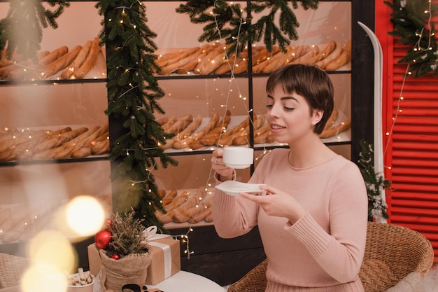 Eine Frau in einem Café trinkt Kaffee oder Tee. Weihnachts- und Neujahrskonzept.