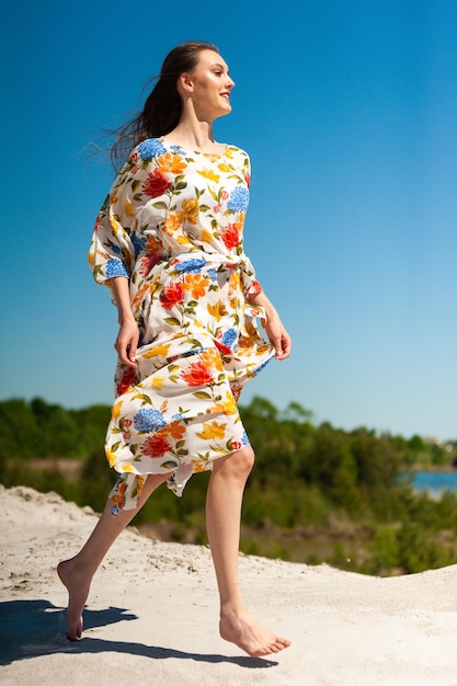 Eine Frau in einem geblümten Kleid geht am Strand spazieren