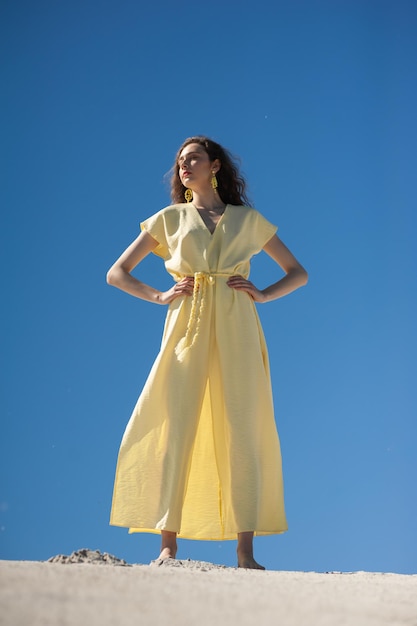 Eine Frau in einem gelben Kleid steht auf einem Hintergrund des blauen Himmels.