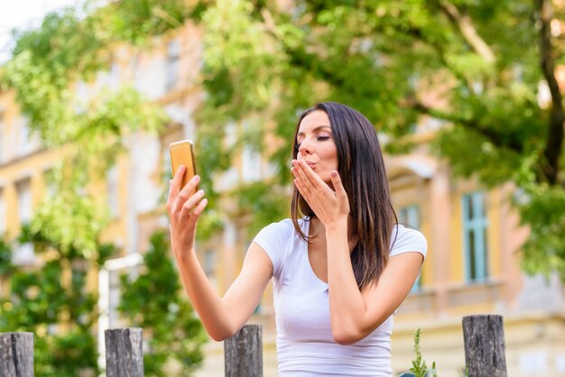 Eine Frau in einem Park, die ein Selfie mit ihrem Smartphone nimmt