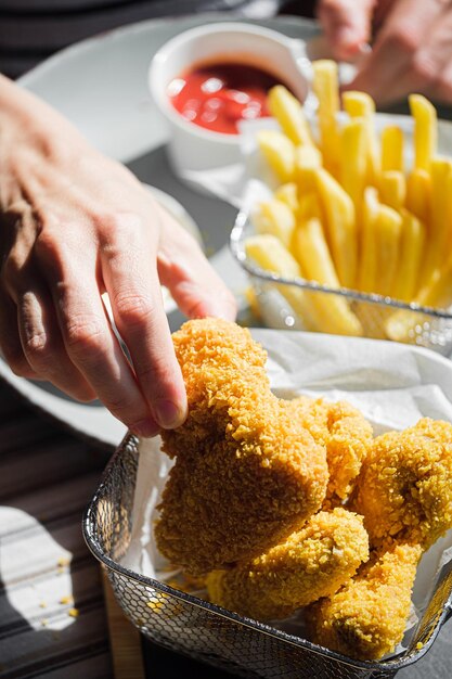 Eine Frau in einem Restaurant oder Fast-Food-Café isst gebratene Flügel in Luftteig mit verschiedenen Saucen und Pommes