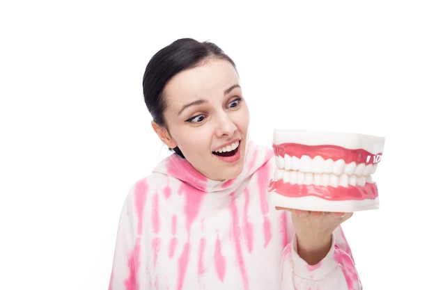 eine frau in einem rosa kapuzenpulli schaut überrascht auf den weißen hintergrund des kiefermodells