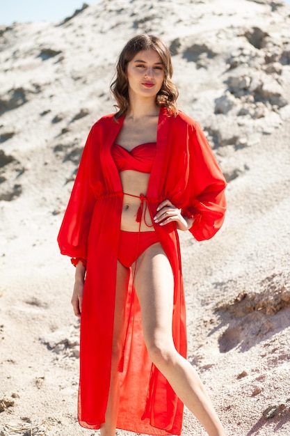 Eine Frau in einem roten Badeanzug steht am Strand.