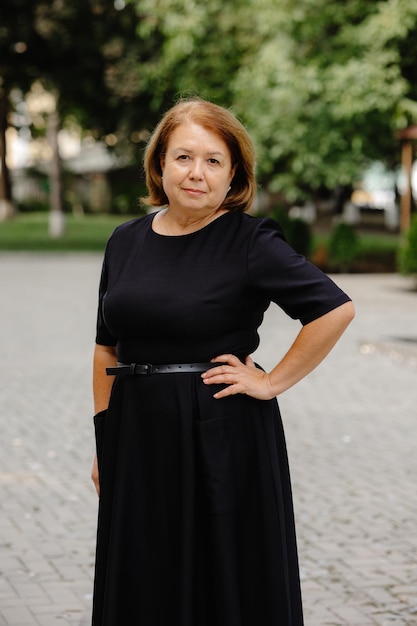 Foto eine frau in einem schwarzen kleid steht in einem park