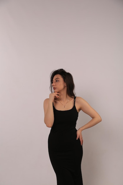 eine Frau in einem schwarzen Kleid steht vor einem weißen Hintergrund